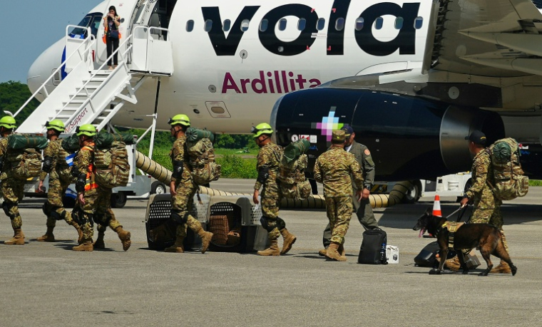 Des militaires salvadoriens accompagnés de chiens renifleurs se préparent à embarquer à bord d’un avion à destination du Venezuela, sur la base aérienne de Comalapa à San Luis Talpa, au Salvador, le 25 juin 2026 ( AFP / Rudy QUIROZ )