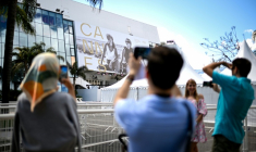 Des passants photographient la façade du Palais du festival à Cannes le 11 mai 2026 ( AFP / Anna KURTH )
