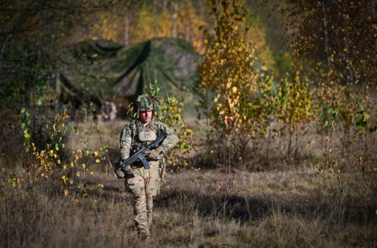 Un soldat français, armé d'un fusil HK416, passe près d'un poste de commandement central dans le champ de tir militaire de Bucium lors de l'exercice "Dacian Fall" de l'Otan, le 2 novembre 2025 en Roumanie ( AFP / Daniel MIHAILESCU )