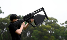Un membre de l'équipe DroneShield tient un fusil "DroneGun" à Sydney, le 9 février 2026 en Australie ( AFP / STEVEN MARKHAM )