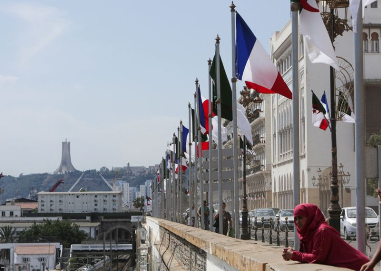 Une femme se tient près des drapeaux algérien et français avant l'arrivée du président français Emmanuel Macron à Alger
