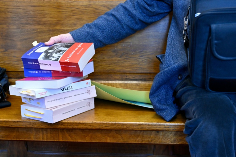 Une pile de livres à côté de Jacques Boncompain, président de l'Association pour défendre la mémoire du Maréchal Pétain (ADMP) lors de son procès devant le tribunal correctionnel de Verdun, le 4 mars 2026 dans la Meuse ( AFP / Jean-Christophe VERHAEGEN )