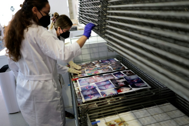 Des étudiants de l'Université des Beaux-Arts nettoient et restaurent des photos de famille par la boue pendant les inondations, le 2 octobre 2025 à Valence, en Espagne ( AFP / Thomas COEX )