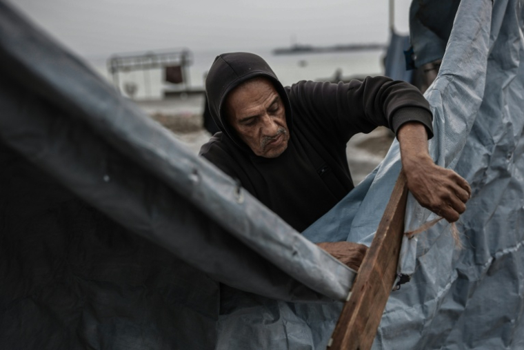 Un homme nettoie sa tente abîmée par la pluie, dans le quartier de Zeitoun à Gaza-ville le 11 décembre 2025 ( AFP / Omar AL-QATTAA )