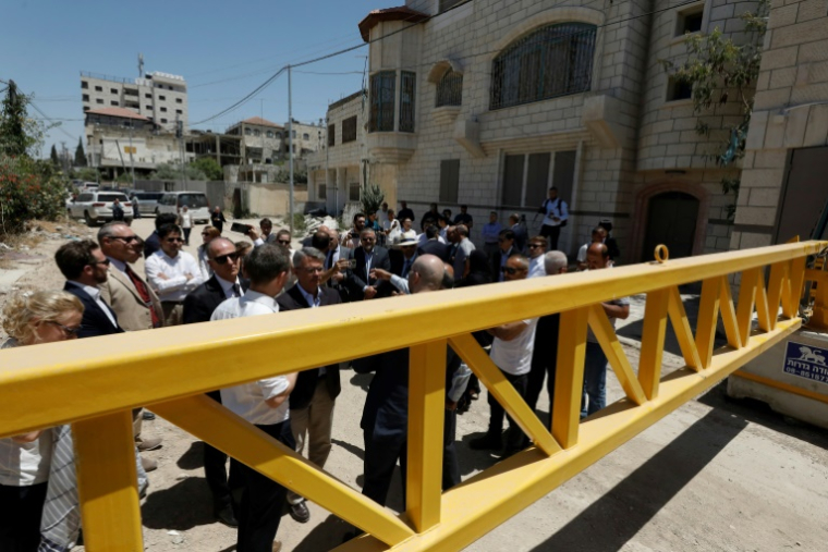 Des membres d’une délégation diplomatique de l’Union européenne se tiennent derrière une grille à l’entrée est du camp de Jénine, lors d’une visite dans cette ville de Cisjordanie occupée, le 21 mai 2025 ( AFP / Mohammad MANSOUR )