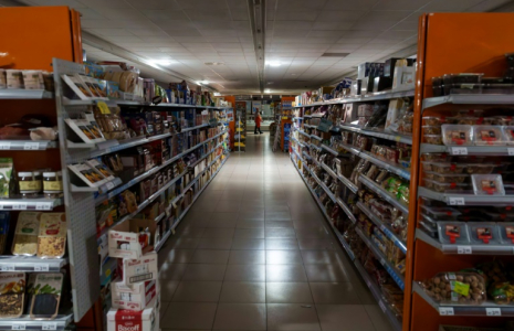 Un employé se tient à l'intérieur d'un supermarch" plongé dans le noir à Burgos, le 28 avril 2025 alors que la péninsule ibérique est affectée par une panné géante d'électricité ( AFP / CESAR MANSO )