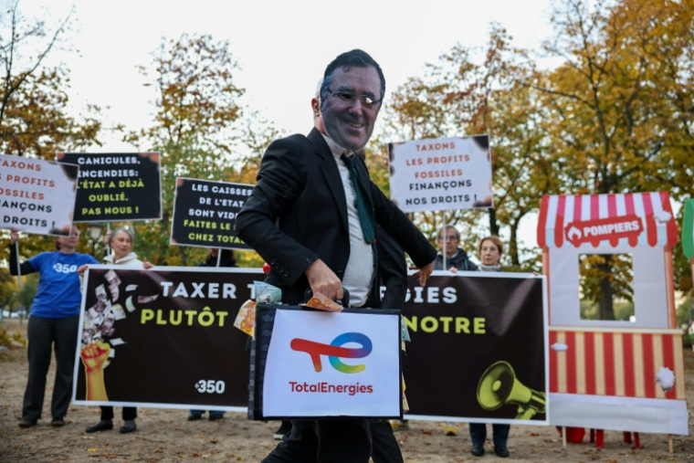 Un militant écologiste porte un masque à l’effigie de Patrick Pouyanné, PDG de TotalEnergies, lors d’une manifestation contre l’austérité gouvernementale et les coupes budgétaires, le 29 octobre 2026 à Paris ( AFP / SIMON WOHLFAHRT )