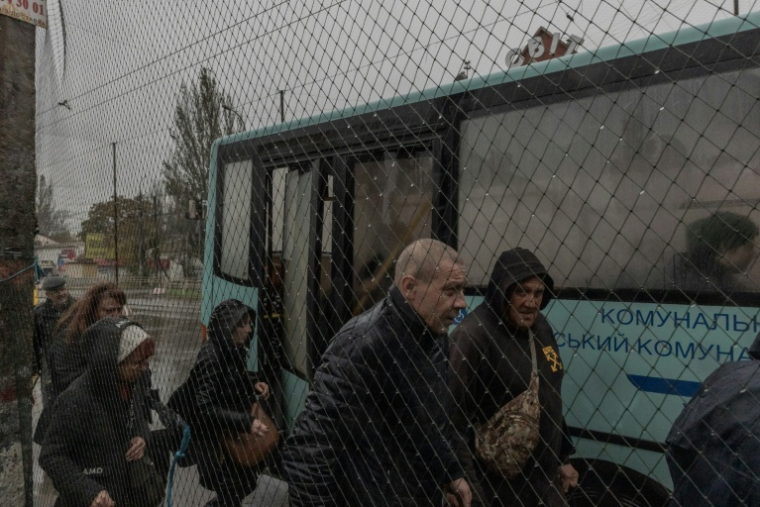 Des passagers à une station de bus où des filets antidrones ont été disposés le long de la route, le 30 octobre 2026 à Kherson, dans le sud de l'Ukraine  ( AFP / Roman PILIPEY )