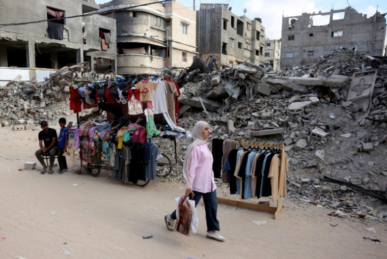 Une Palestinienne marche devant un étal de vêtements avant l'Aïd al-Adha, la fête du sacrifice, à Khan Younès, dans le sud de la bande de Gaza, le 26 mai 2026 ( AFP / Bashar Taleb )