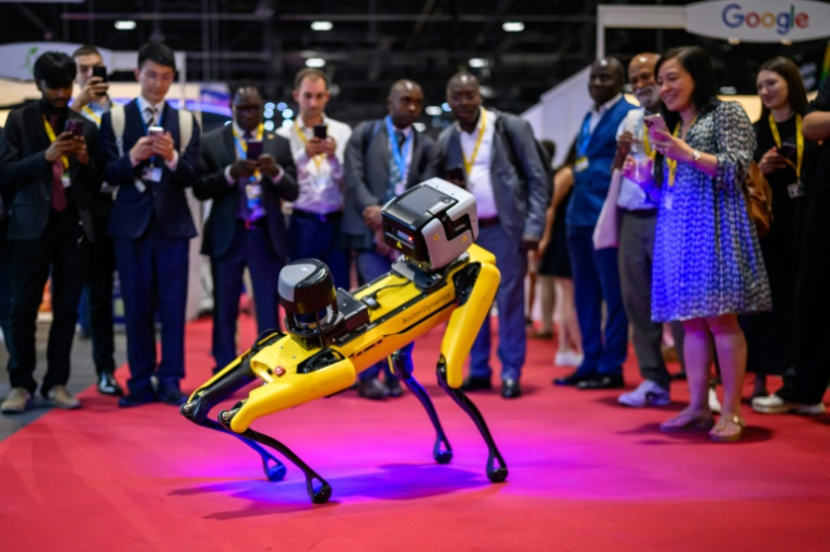 Des visiteurs photographient un robot de Boston Dynamics ressemblant à un chien, lors du Sommet mondial AI for Good", un événement des Nations unies, le 7 juillet 2026 à Genève ( AFP / Fabrice COFFRINI )