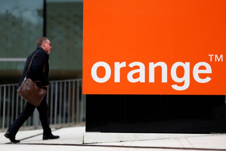 Un homme passe devant le logo Orange près de Paris