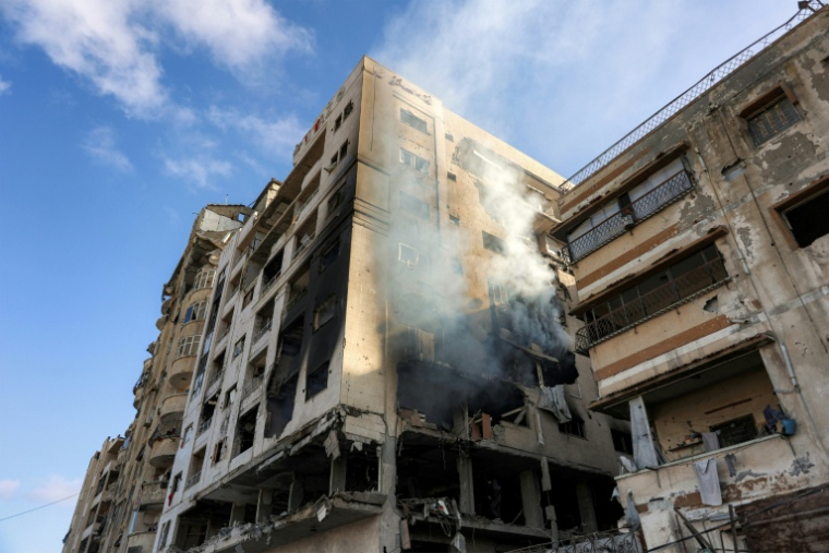 De la fumée s'échappe d'un immeuble résidentiel touché la veille par une frappe israélienne dans le quartier d'Al-Ramal à Gaza, le 16 mai 2026 ( AFP / Omar AL-QATTAA )