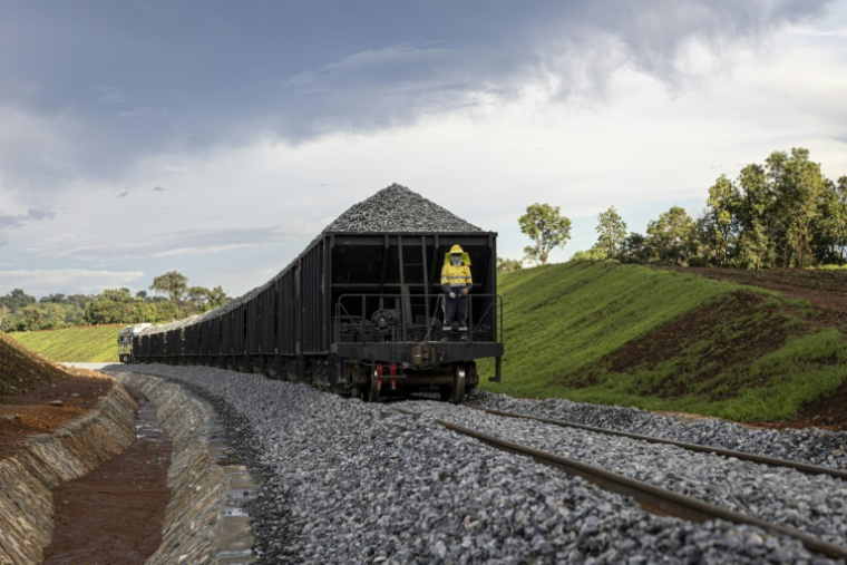 Un employé de la compagnie chinoise China Railway 18th Bureau Group à l'arrière d'un train transportant des pierres à la mine de Simfer, dans les montagnes de Simandou, le 2 septembre 2025 en Guinée ( AFP / PATRICK MEINHARDT )