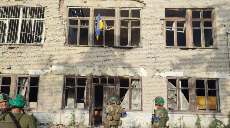 Des soldats ukrainiens devant un bâtiment portant le drapeau ukrainien, lors d'une contre-offensive, à Blahodatne, dans la région de Donetsk, en Ukraine.