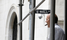 Un homme fume un cigare sur Wall St. à l'extérieur de la Bourse de New York