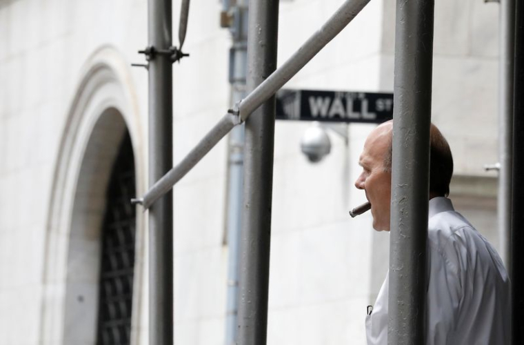 Un homme fume un cigare sur Wall St. à l'extérieur de la Bourse de New York