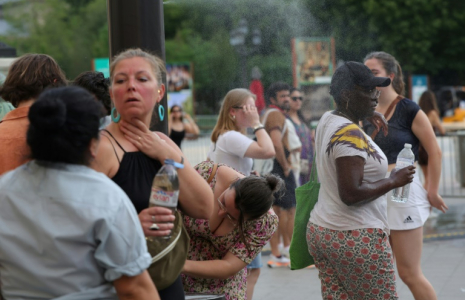 Des personnes se rafraîchissent en traversant un fin brouillard d'eau dans le centre de Paris le 21 juin 2025 ( AFP / ROMAIN PERROCHEAU )