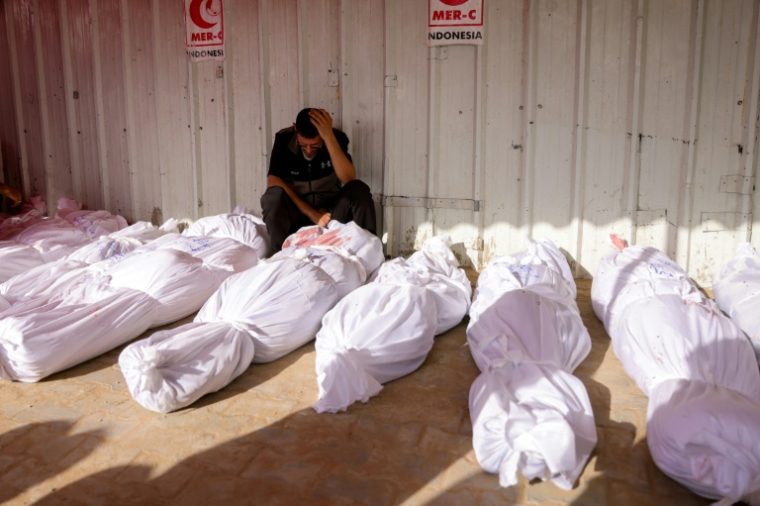 Une homme se recueille devant les corps de victimes de raids israéliens, à l'hôpital indonésien de Jabalia, dans le nord de la bande de Gaza, le 14 mai 2025 ( AFP / BASHAR TALEB )