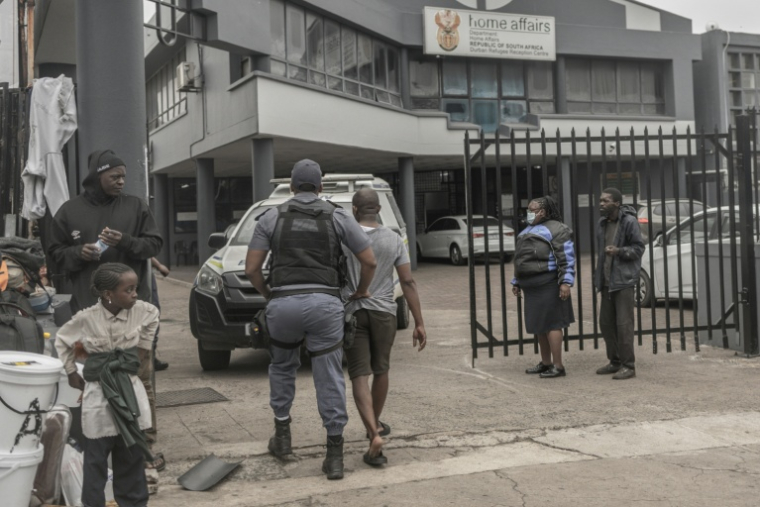 Un policier sud-africain interpelle un ressortissant étranger soupçonné d’être en situation irrégulière lors d’une opération de contrôle et de fouille dans le centre de Durban, le 29 juin 2026 ( AFP / RAJESH JANTILAL )
