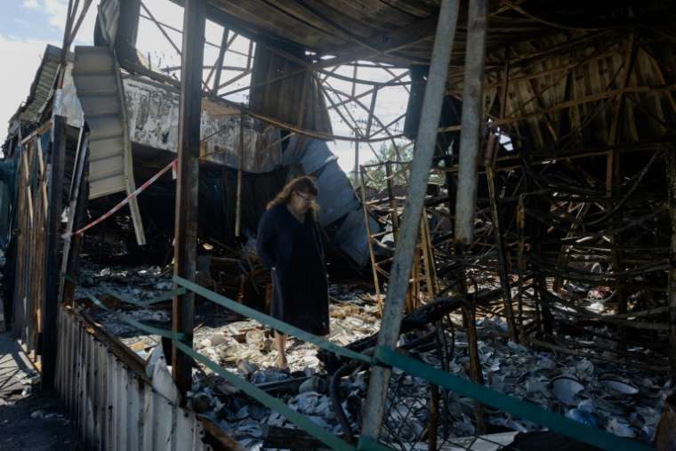 Une femme au milieu des débris de porcelaines brisées sur le marché aux puces de Potchaïna endommagé par une frappe russe, le 9 août 2026 à Kiev, en Ukraine ( AFP / Tetiana DZHAFAROVA )