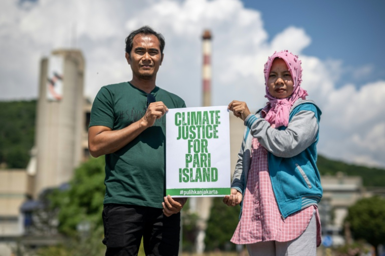 Edi (g) et Asmania, deux habitants de l'île indonésienne de Pari, posent pour une photo le 11 juin 2023 à côté de l'usine du géant suisse du ciment Holcim à Eclepens, dans l'ouest de la Suisse ( AFP / Fabrice COFFRINI )