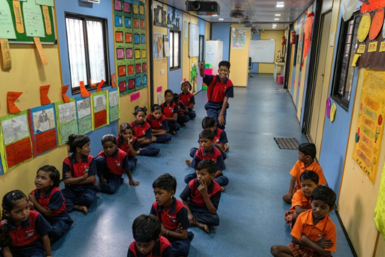 Des élèves dans "l'école du feu rouge", qui accueille des enfants défavorisés dans des conteneurs aménagés en salles de cours sous un pont autoroutier, le 18 mai 2026 à Bombay ( AFP / Punit PARANJPE )