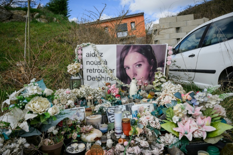 Des bougies et des fleurs déposées devant un portrait de Delphine Jubillar, près de sa maison à Cagnac-les-Mines, le 6 mars 2025 dans le Tarn ( AFP / Lionel BONAVENTURE )