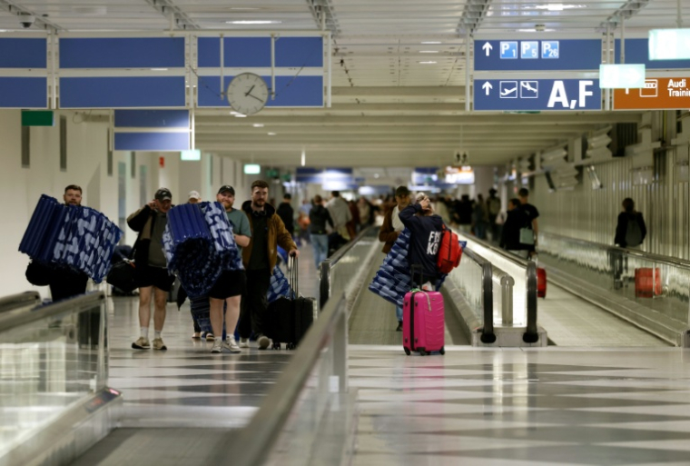Des voyageurs transportent des matelas gonflables qui leur ont été fournis pour dormir à l'aéroport international de Munich, après que des rapports d'observations de drones ont de nouveau forcé l'aéroport à fermer, le 4 octobre 2025 dans le sud de l'Allemagne ( AFP / Michaela STACHE )