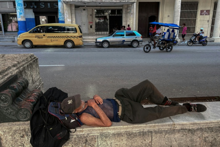 Un homme dort sur un muret, le 14 juillet 2026  dans une rue de La Havane, lors d'une panne d'électricité nationale à Cuba ( AFP / YAMIL LAGE )