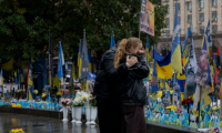Des passants devant un mémorial improvisé pour les soldats ukrainiens et étrangers morts au combat, le 7 octobre 2025 à Kiev  ( AFP / Tetiana DZHAFAROVA )