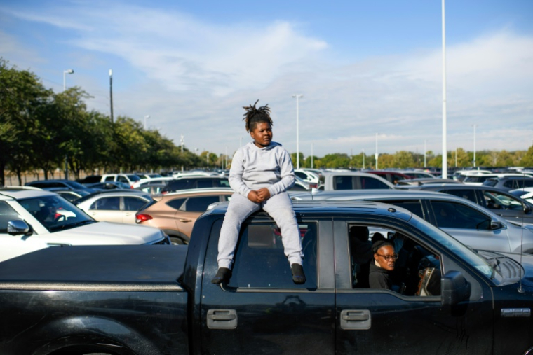 Un enfant sur le toit du pick-up familial attend une distribution d'aide alimentaire à Houston, au Texas, le 1er novembre 2025 ( AFP / Mark Felix )