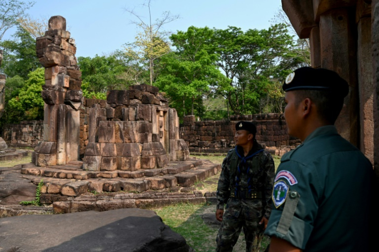 Un soldat cambodgien, à droite, et un soldat thaïlandais montent la garde devant le temple khmer de Prasat, revendiqué par leur deux pays et situé dans la province cambodgienne d'Oddar Meanchey, près de leur frontière, le 26 mars 2025 ( AFP / TANG CHHIN Sothy )