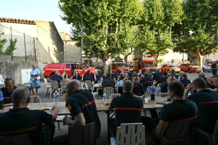Les sapeurs-pompiers venus en renfort dans l'Aude lors d'un repas organisé en leur honneur à Talairan, dans l'Aude, le 8 août 2025 ( AFP / Bertrand GUAY )