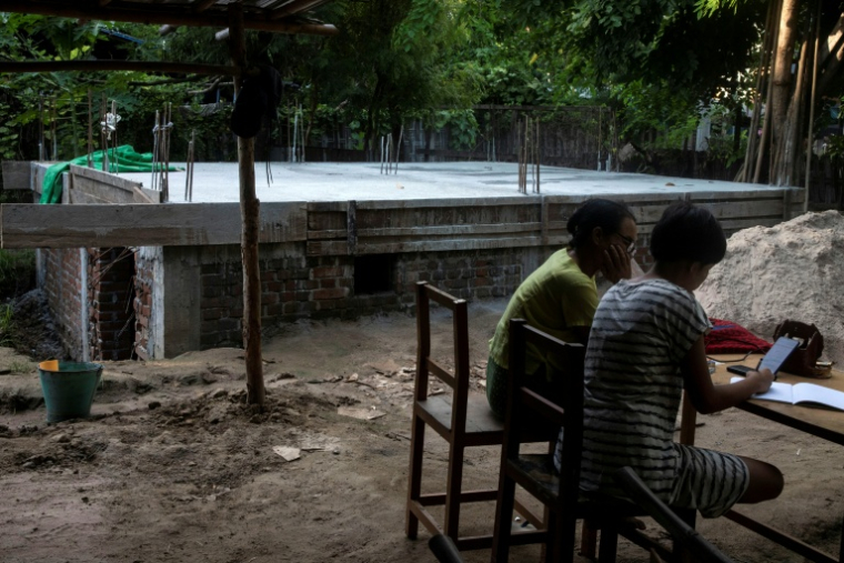 Cette photo prise le 15 août 2025 montre des élèves étudiant à côté d'un bunker en béton qui abrite leur école pour se protéger des frappes aériennes dans un village de la région de Sagaing, en Birmanie. ( AFP / STR )