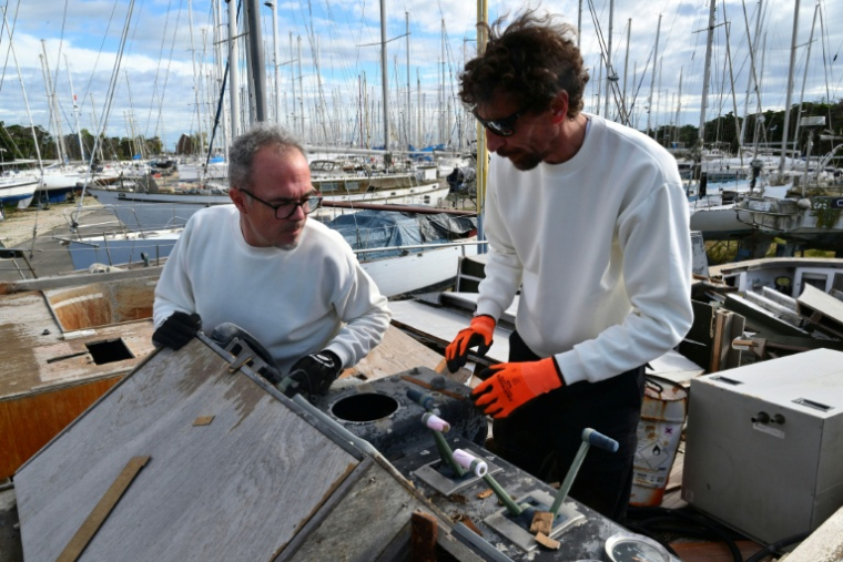 Thomas Bekkers (G) et Guillaume Delaunay cherchent des pièces réutilisables ou recyclables pour leur ressourcerie spécialisée dans le matériel maritime et nautique, le 7 novembre 2025 dans un cimetière de bateaux à Port-Saint-Louis-du-Rhône, dans les Bouches-du-Rhône ( AFP / Christophe SIMON )