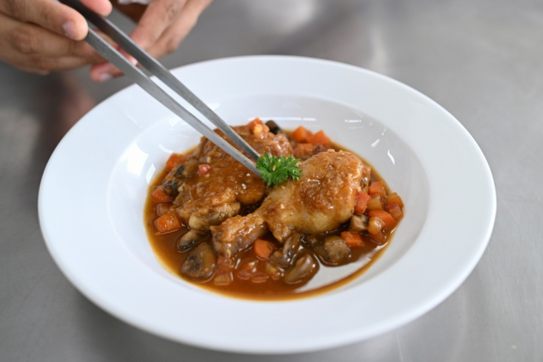 Un élève-cuisinier dresse un poulet sauté chasseur à l'École Ducasse de Gurugram, en Inde, le 22 septembre 2026 ( AFP / Arun SANKAR )