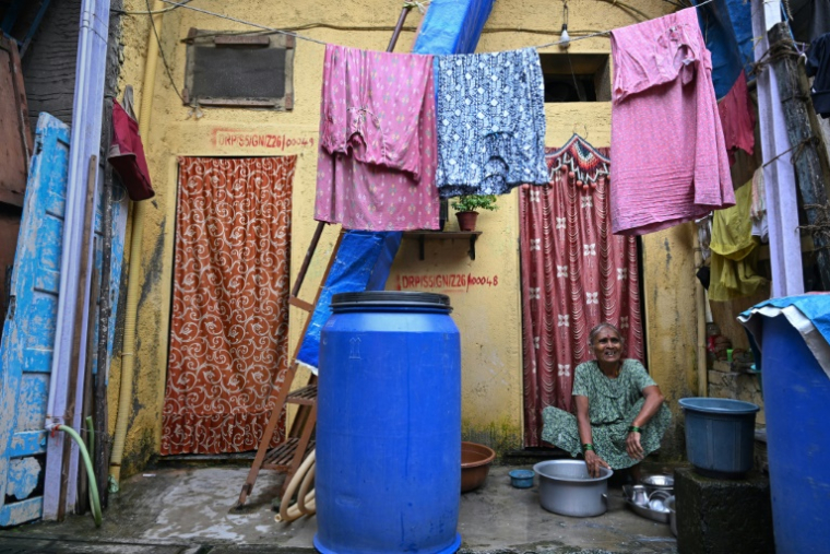 Une habitante, éligible à la relocalisation dans le cadre d'un projet de rénovation urbaine, lave des ustensiles devant son logement du bidonville de Dharavi, le 9 juillet 2025 à Bombay, en Inde ( AFP / Indranil MUKHERJEE )