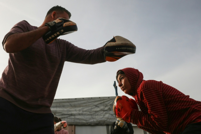 L'entraîneur de boxe Ossama Ayoub et une de ses élèves lors d'un entraînement à Khan Younès, dans le sud de la bande de Gaza, le 9 février 2026 ( AFP / BASHAR TALEB )