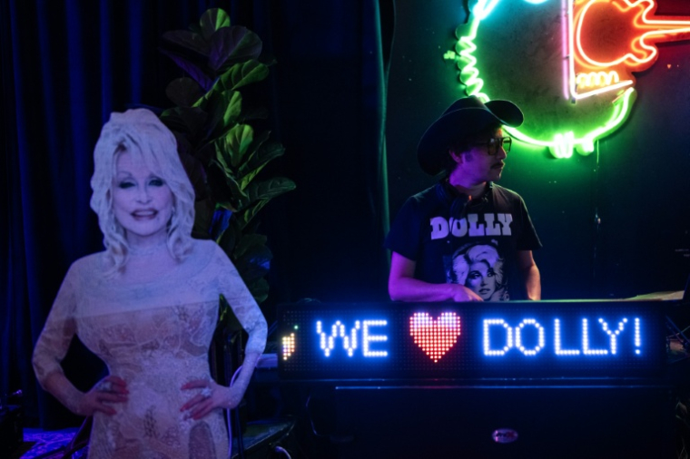 Un DJ joue de la musique à côté d’une silhouette en carton de la stard américaine de la country Dolly Parton, lors d’une soirée en son honneur dans un bar de Houston, au Texas, le 26 août 2026 ( AFP / RONALDO SCHEMIDT )