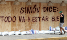 Un homme passe devant un message: "Simon a dit: +tout va bien se passer+", peint sur des planches de protection en prévision de l'arrivée du cyclone Simon à Puerto Vallarta au Mexique, le 10 octobre 2026 ( AFP / ULISES RUIZ )