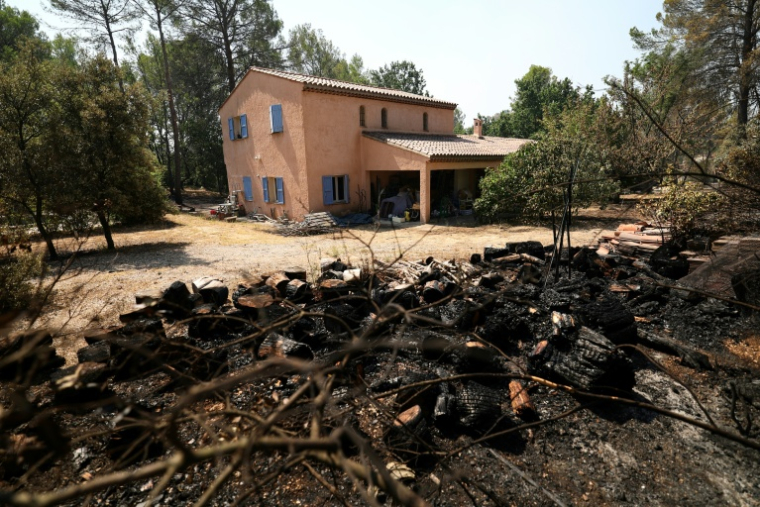 Des arbres brûlés dans un incendie de forêt devant une maison épargnée par les flammes  à Montfort-sur-Argens, dans le Var, le 1er août 2026 ( AFP / Clement MAHOUDEAU )