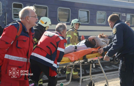 Photo diffusée par le Service ukrainien des situations d'urgence le 29 octobre 2026 montrant des secouristes ukrainiens transportant sur une civière une personne blessée après une attaque aérienne contre la gare de Dnipro, en Ukraine ( UKRAINIAN EMERGENCY SERVICE / Handout )