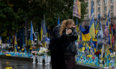Des passants devant un mémorial improvisé pour les soldats ukrainiens et étrangers morts au combat, le 7 octobre 2025 à Kiev  ( AFP / Tetiana DZHAFAROVA )