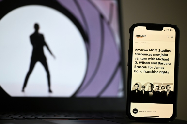 Un article d'Amazon affiché sur un smartphone, avec une illustration de la franchise James Bond en arrière-plan, le 23 février 2025 ( AFP / Justin TALLIS )