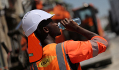Un travailleur boit de l'eau sur un chantier de construction, lors d'une journée chaude et ensoleillée à Nantes