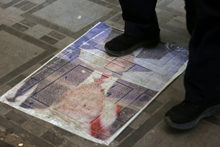 Un Iranien marche sur un portrait du président américain Donald Trump installé sur le sol de la ville-frontière de Zurbatiyah, en Irak, le 29 juillet 2026 ( AFP / AHMAD AL-RUBAYE )