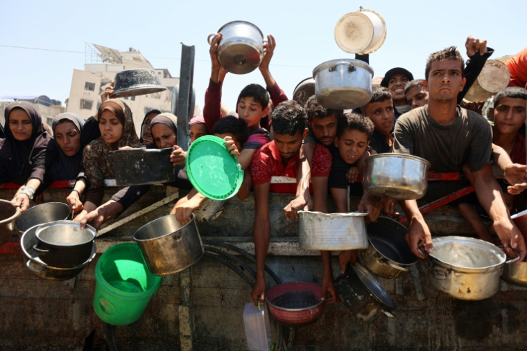 Des Palestiniens affamés attendent de recevoir une ration de soupe de lentilles lors d'une distribution alimentaire à Gaza, le 2 août 2025 ( AFP / Omar AL-QATTAA )