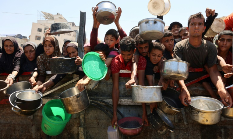 Des Palestiniens affamés attendent de recevoir une ration de soupe de lentilles lors d'une distribution alimentaire à Gaza, le 2 août 2025 ( AFP / Omar AL-QATTAA )