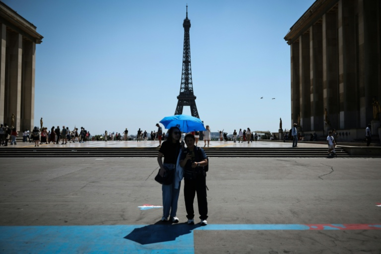 Des touristes se protègen du soleil au Trocadéro à Paris, le 18 juin 2026 ( AFP / Simon WOHLFAHRT )