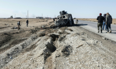 Un mort gît derrière un véhicule militaire kurde détruit au sud de la ville à majorité kurde d'Hassaké, dans le nord-est de la Syrie, le 20 janvier 2026 ( AFP / Bakr ALkasem )